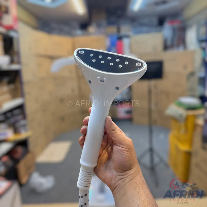 Handheld white garment steamer with a dark grey soleplate featuring multiple steam vents.