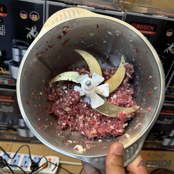 A stainless steel food chopper with three blades, containing ground meat.