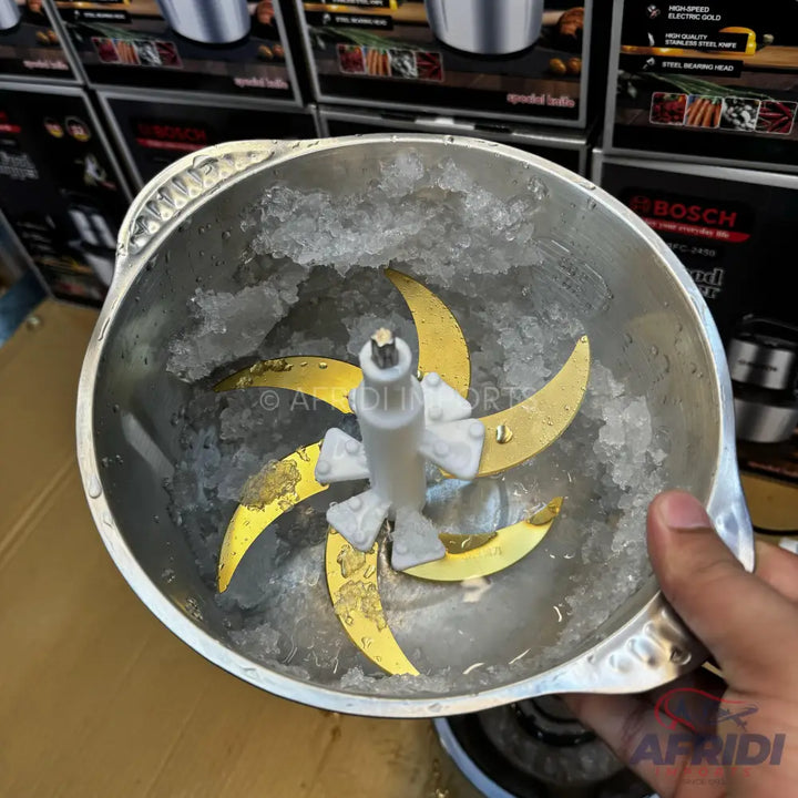A metal food processor bowl with six gold-colored blades and crushed ice.