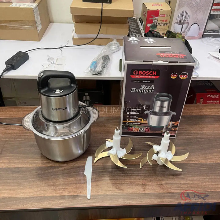 Stainless steel food chopper with a black top and multiple blade attachments.
