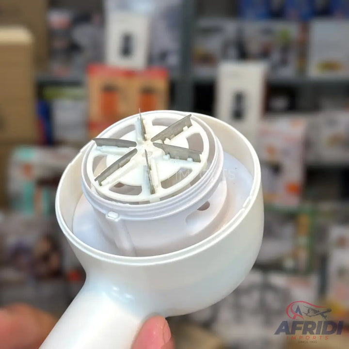 A handheld white garlic press or food grater with a rotating blade mechanism.