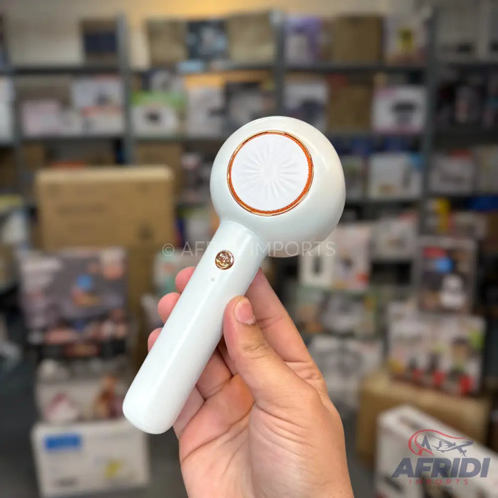 White handheld portable fan with a round head and a gold-colored trim and button.