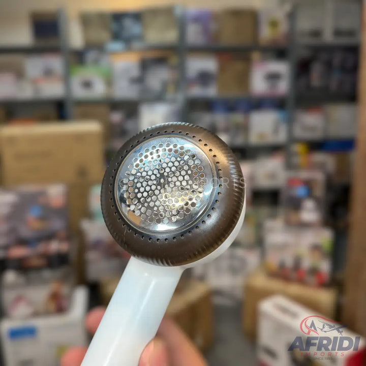 White and brown handheld fabric shaver with a perforated metal head.