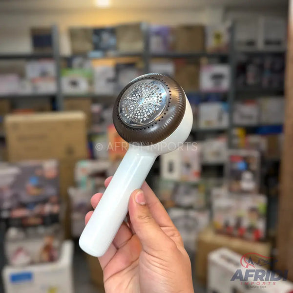 White and brown handheld lint remover with a perforated metal head.
