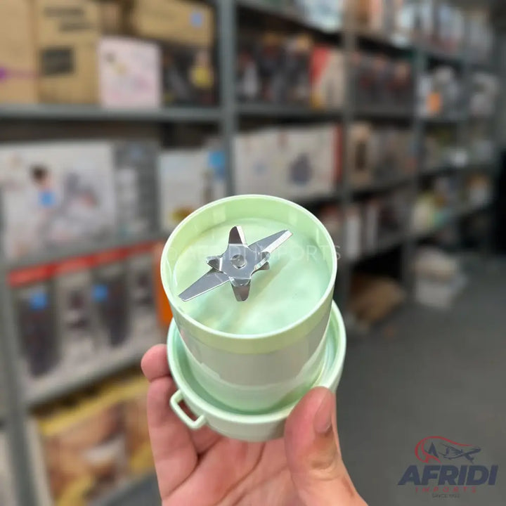 A pale green, compact food processor or blender component with a two-pronged blade.