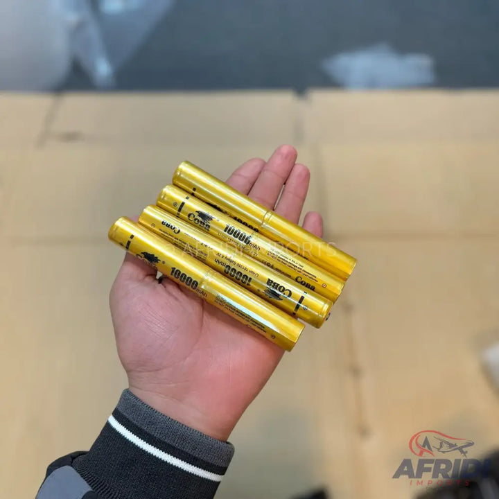 A hand holding five golden yellow cylindrical objects, possibly batteries or power banks.