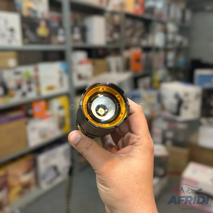 Handheld black and gold flashlight with a bright LED bulb.
