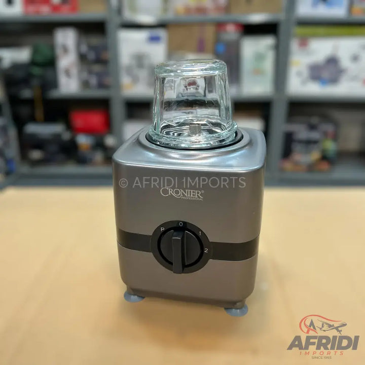 A compact electric coffee grinder with a gray and silver finish, a clear glass grinding cup, and a black rotary control dial with pulse and two speed settings.