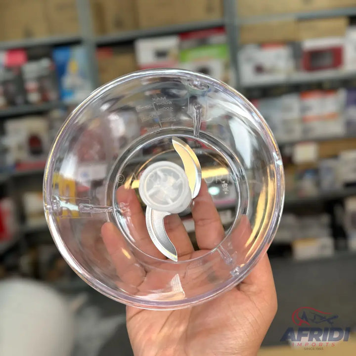 A transparent plastic food chopper bowl with a two-bladed metal chopping attachment.