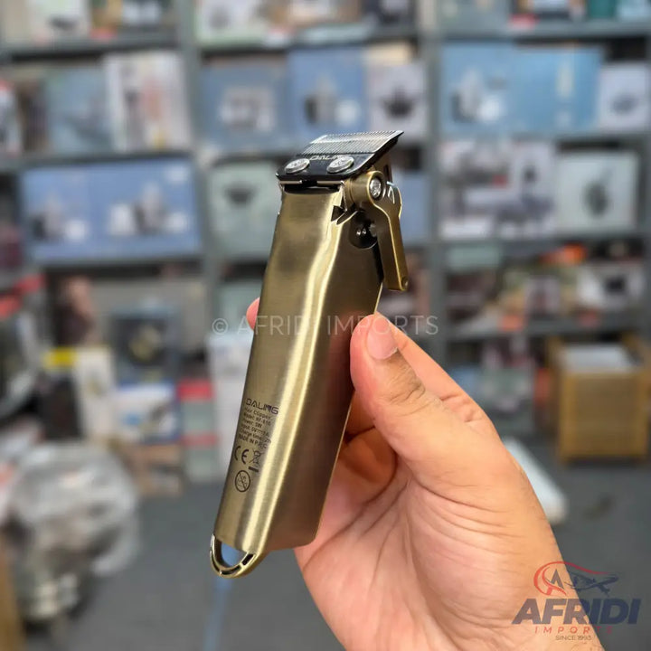 A metallic bronze hair clipper with a black blade, held in a hand.