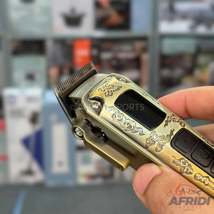 An antique brass-colored hair clipper with intricate cloud patterns and a digital display.