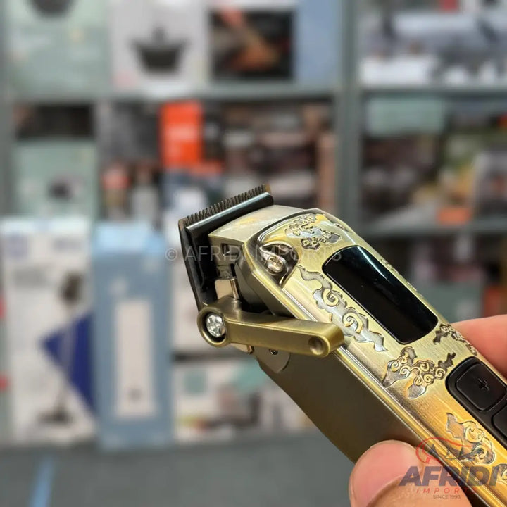 Gold-colored electric hair clipper with intricate design.