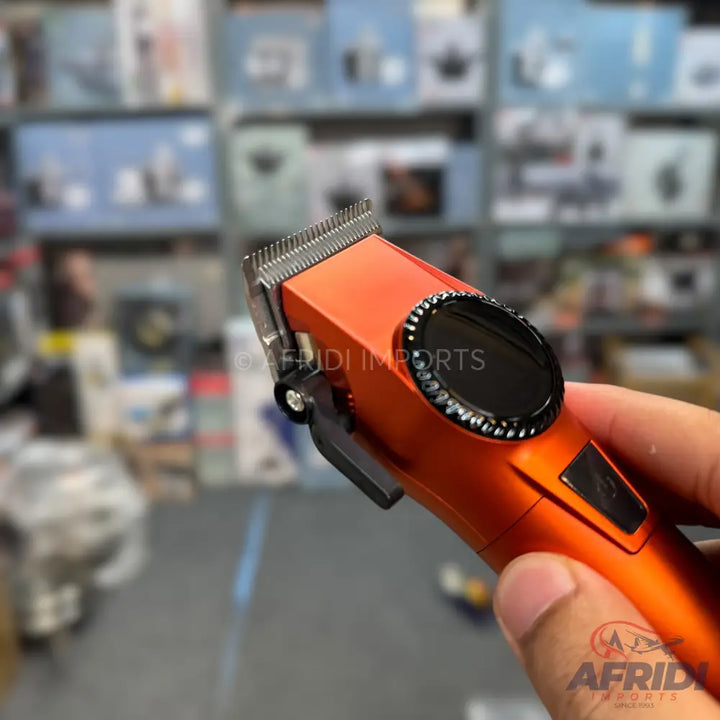 Orange hair clipper with a black digital display and a lever on the side.