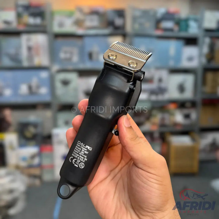 Black electric hair clipper held in a hand.