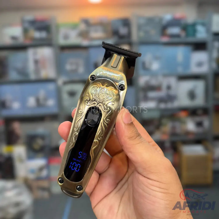 A gold-colored electric hair trimmer with an ornate design and a digital display showing battery percentage.