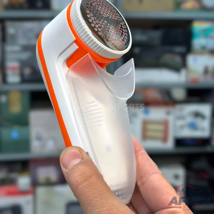 White and orange electric lint remover with a clear collection compartment.