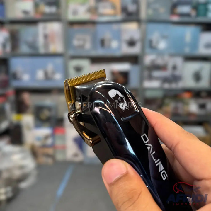A black electric hair clipper with a gold-colored blade.