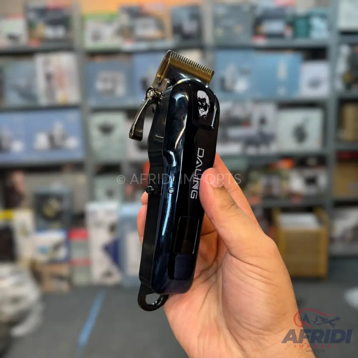 A black hair clipper with a gold-colored blade and a skull design.