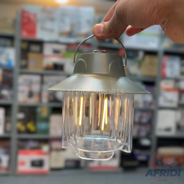 A vintage-style portable LED lantern with a metal top and a clear, fluted glass body.
