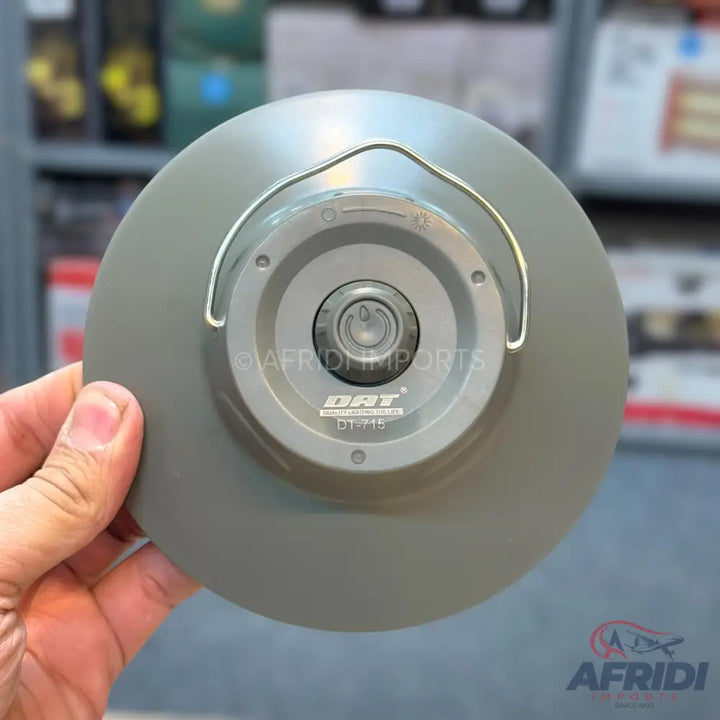 A portable, round, grey LED light with a hanging hook and a central power button.