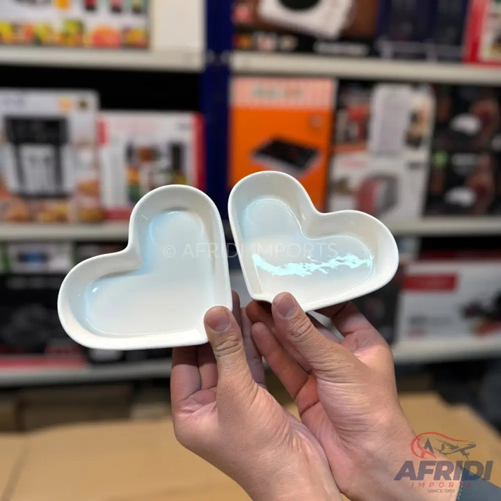 Two white, heart-shaped ceramic dishes with an iridescent sheen.