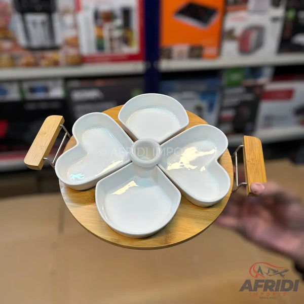 A five-section, heart-shaped ceramic serving dish set on a round wooden tray with two wooden handles.