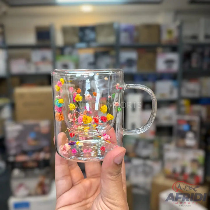 Clear double-walled glass mug with colorful dried flowers embedded between the layers.