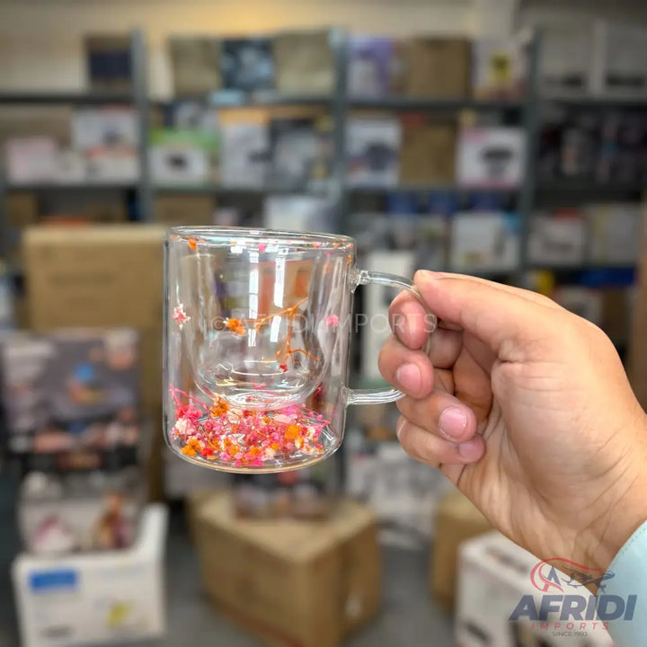 A double-walled glass mug with a built-in infuser, filled with colorful dried flowers.