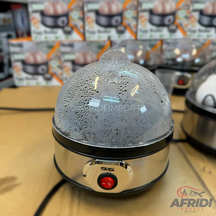 A stainless steel electric egg cooker with a clear, condensation-covered dome lid and a red on/off switch.