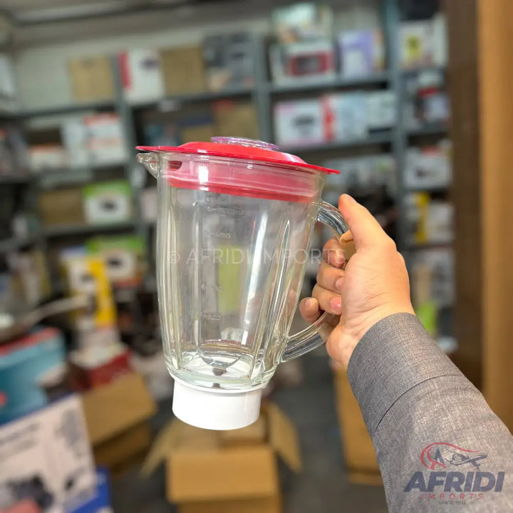 Clear glass blender jar with a red lid and white base.