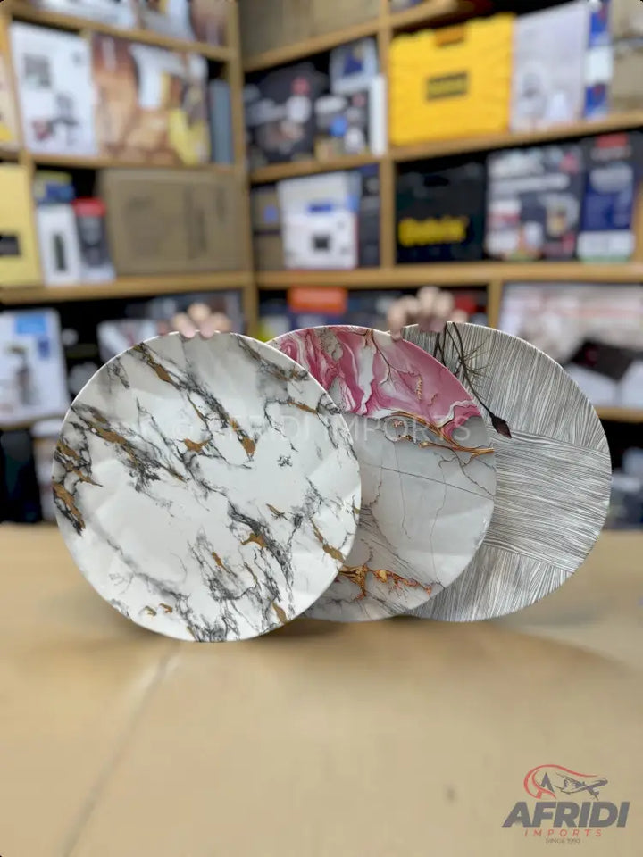 Three decorative round plates, each with a unique abstract or marble-like pattern in different colors.