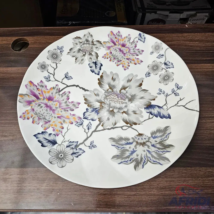White round plate with a floral design featuring purple, grey, and blue flowers and dark branches.