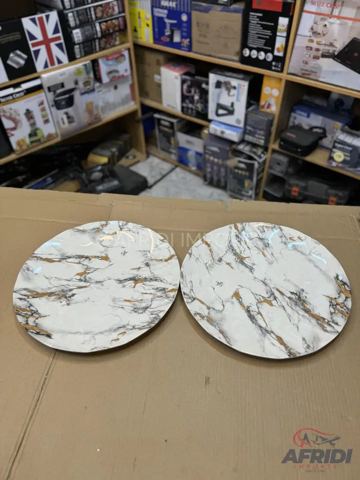 Two round, white marble-patterned dinner plates with gold and gray veining.