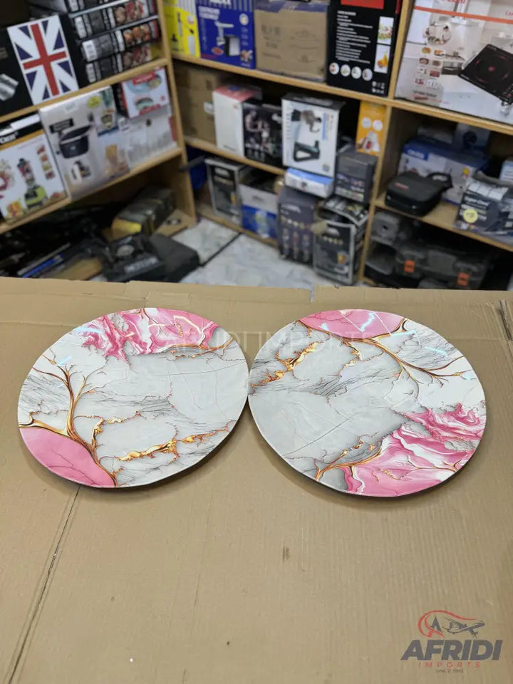 Two round decorative plates with pink, white, and gold marble patterns.