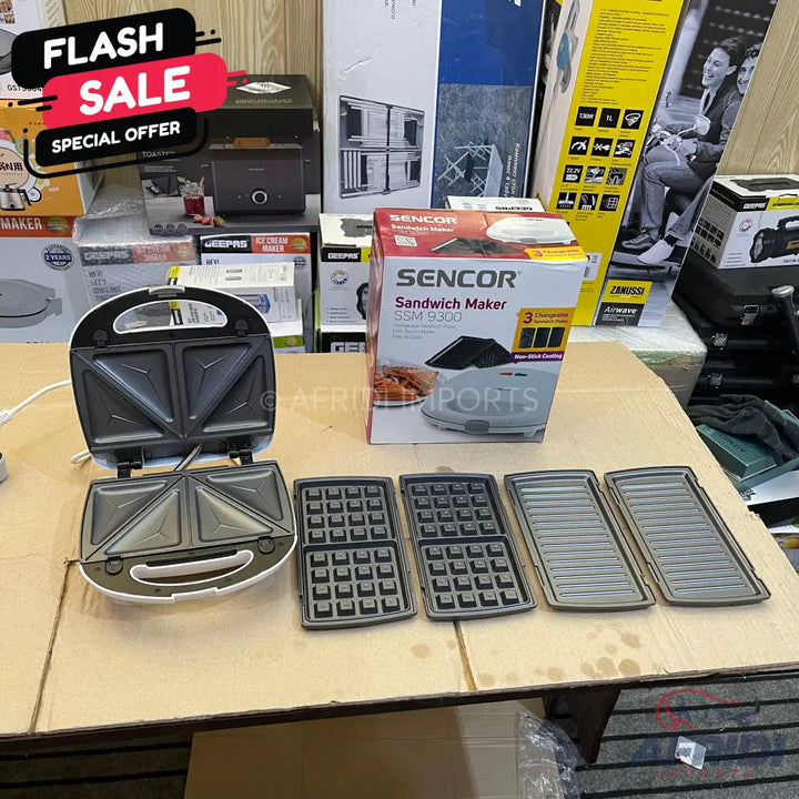White Sencor sandwich maker with three sets of interchangeable plates for sandwiches, waffles, and grilling.