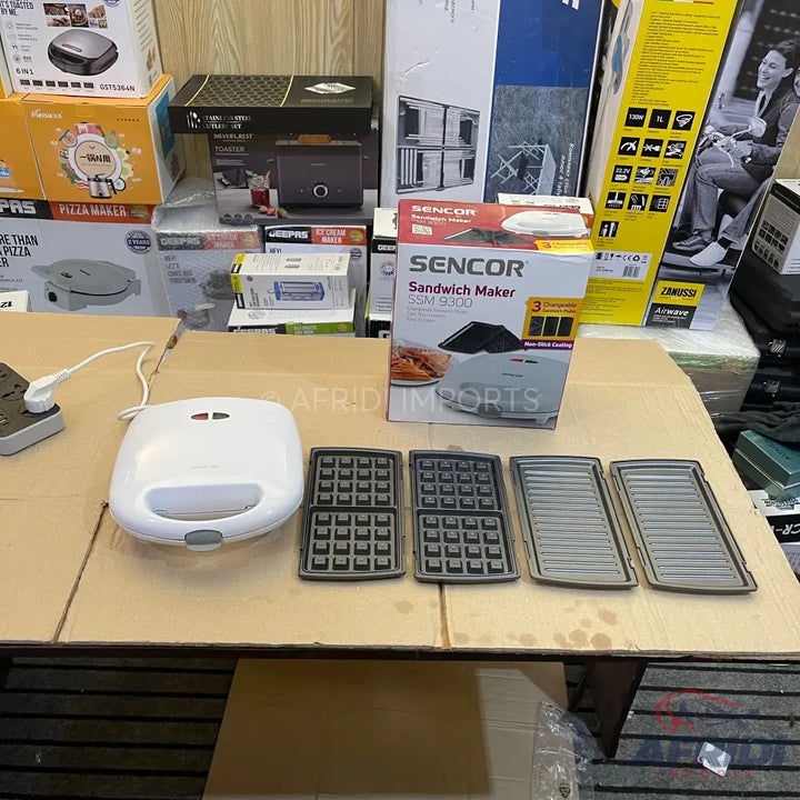 A white sandwich maker with interchangeable waffle and grill plates.