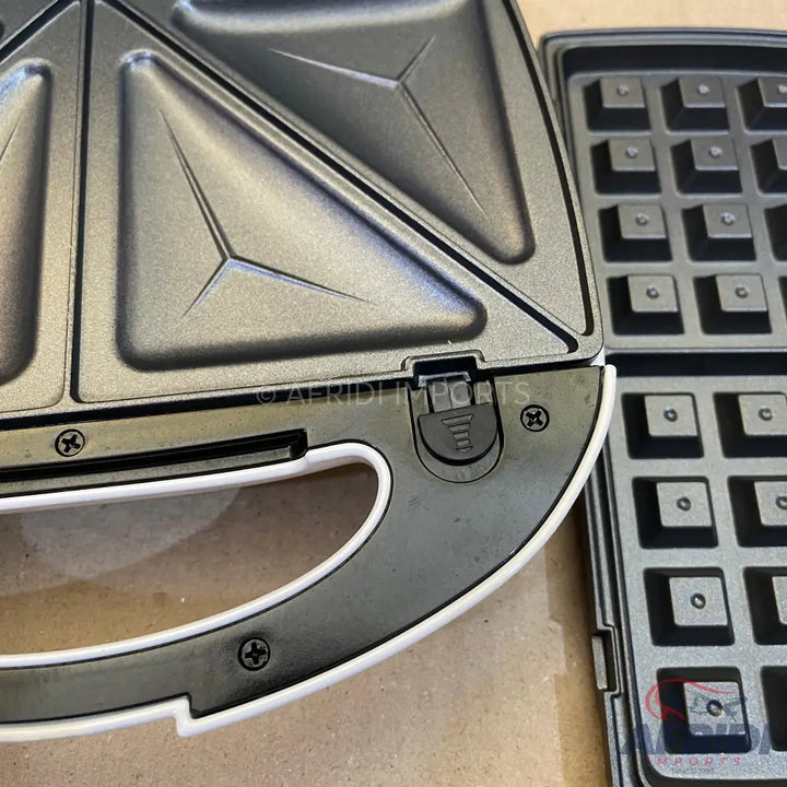A black and white sandwich maker with interchangeable waffle plates.
