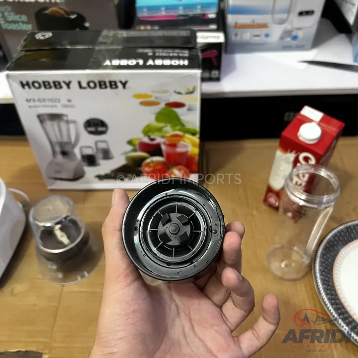 A person’s hand holding a blender base with a blade assembly.