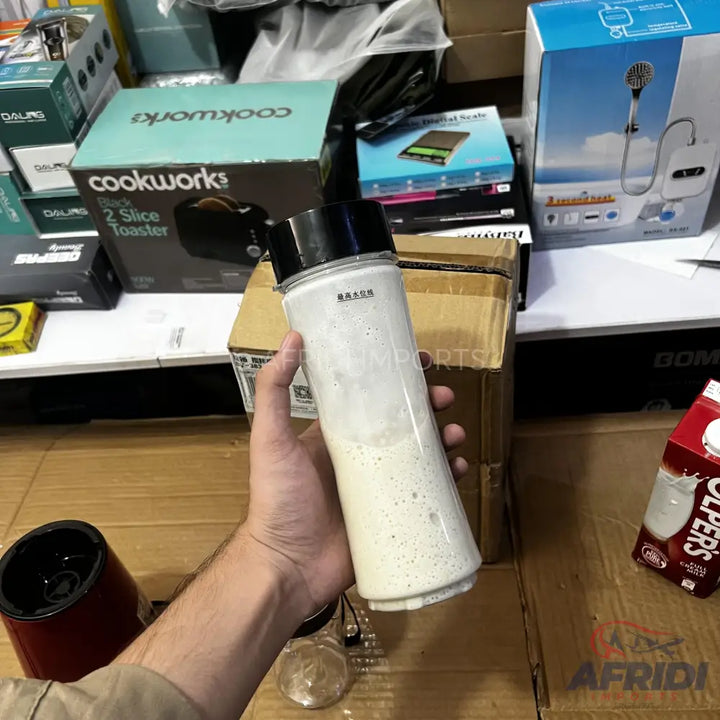 A clear portable blender bottle with a black lid and a creamy white liquid inside.