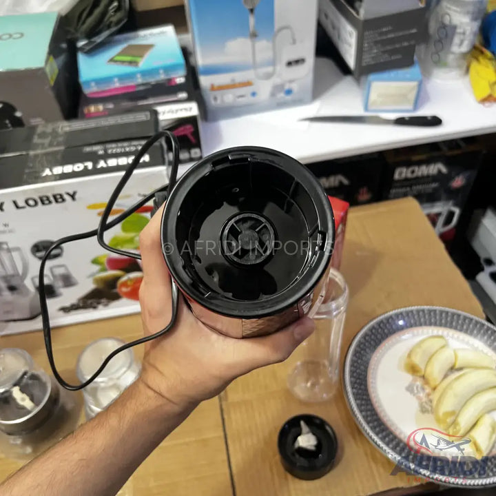 A hand-held electric food grinder with a black top and a transparent container, suitable for processing ingredients like garlic.