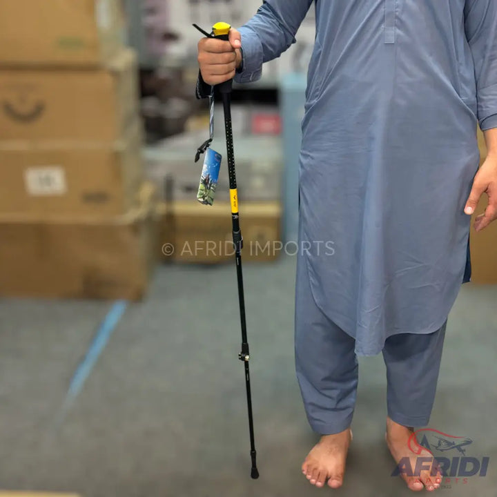Black trekking pole with a yellow handle and a hanging tag.