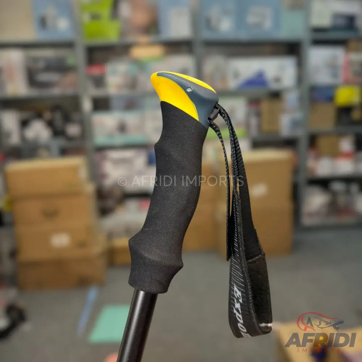 Black and yellow trekking pole with an ergonomic grip and wrist strap.
