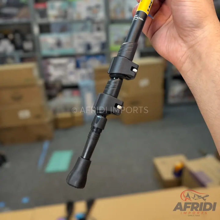Black collapsible trekking pole with adjustable clips and a yellow top section.