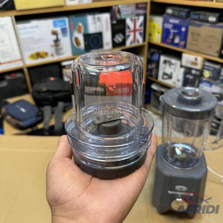 A clear plastic blender cup with a dark gray base and a two-blade attachment.