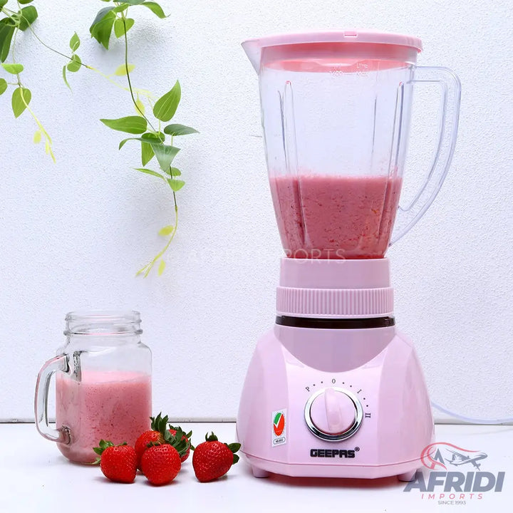 Pink blender with a clear pitcher filled with strawberry smoothie.