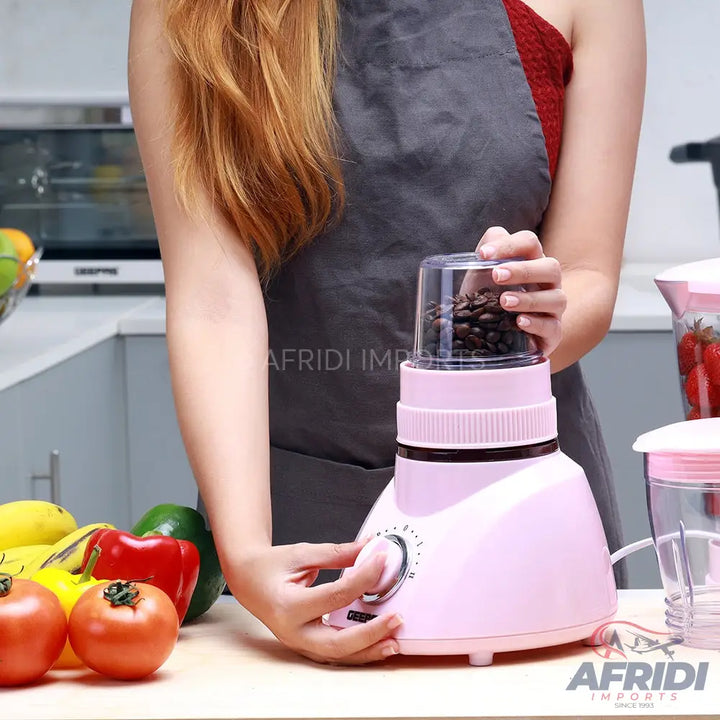 Pink electric coffee grinder with a clear top chamber filled with coffee beans.