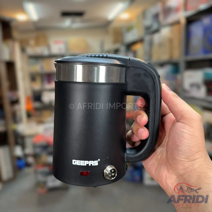 Black portable electric kettle with a handle, a power indicator light, and a power input port.