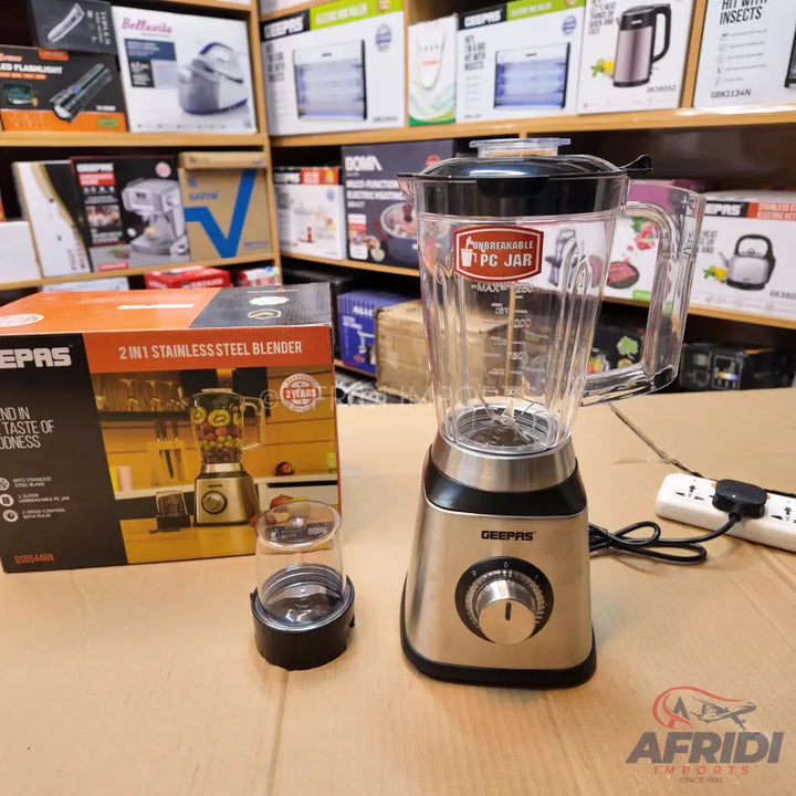A stainless steel blender with a clear plastic jar and a small grinder attachment.