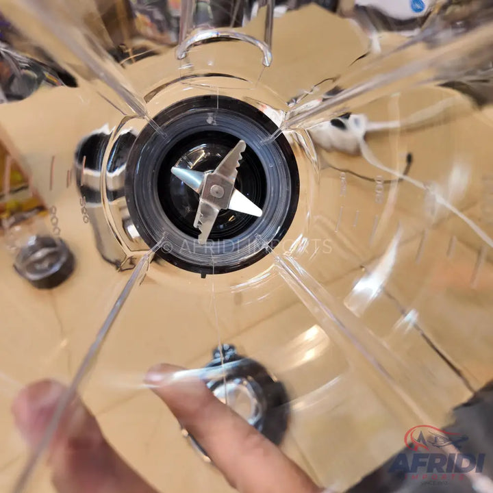 A clear plastic blender jar with a four-pronged blade assembly at its base.