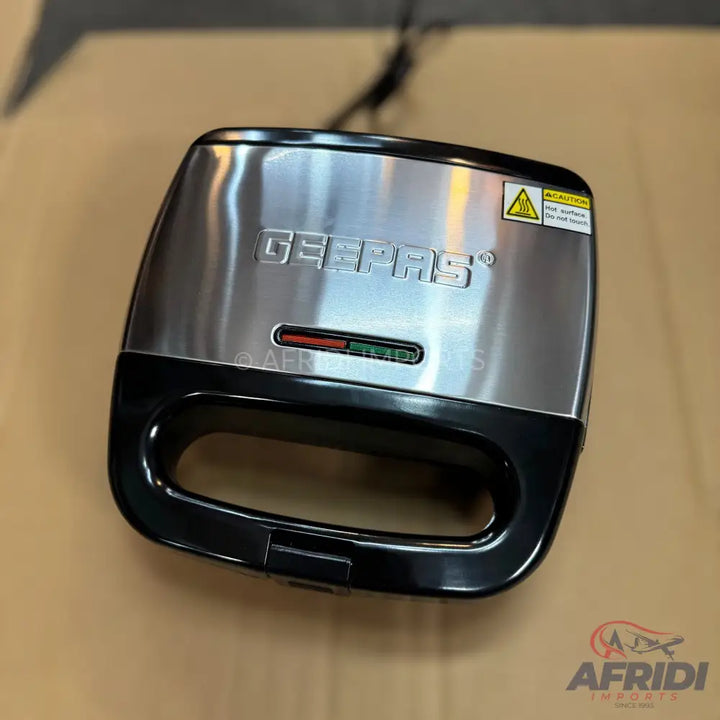 A silver and black sandwich maker with indicator lights.